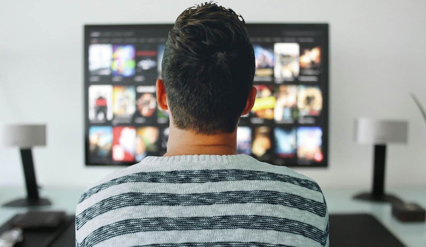 back of head of a guy looking at a television - types of advertising 